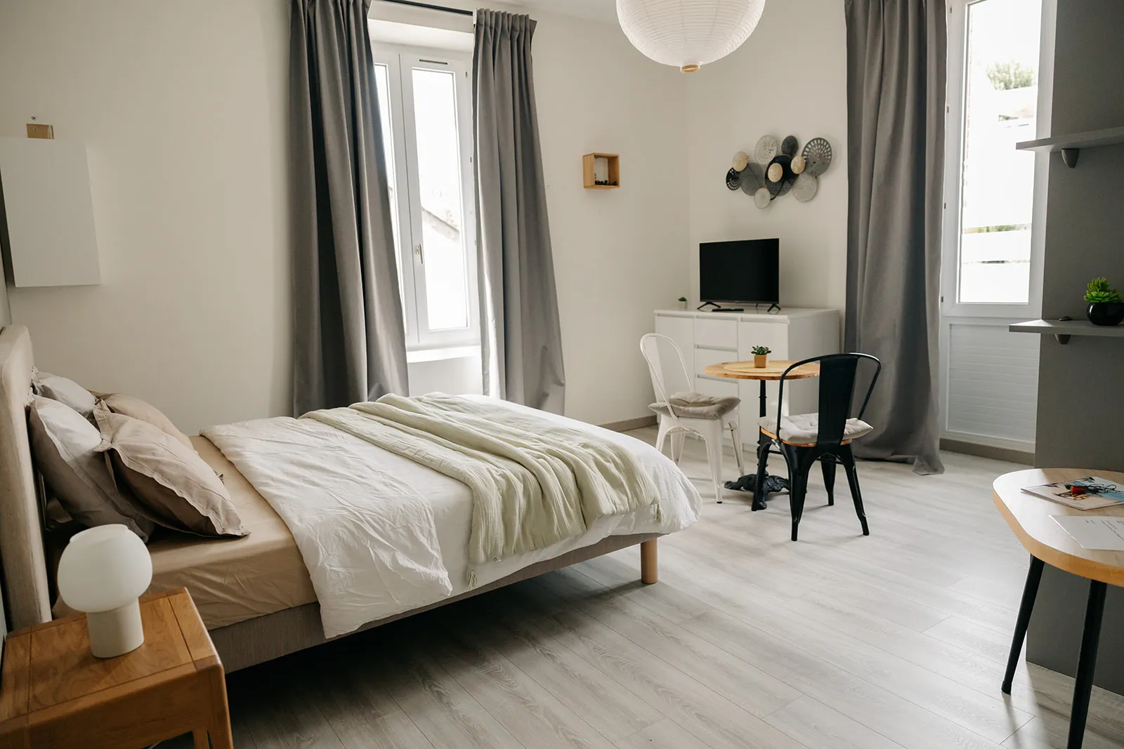 Vue d’ensemble du studio Cosy Pornic : lit queen, coin repas et grandes fenêtres