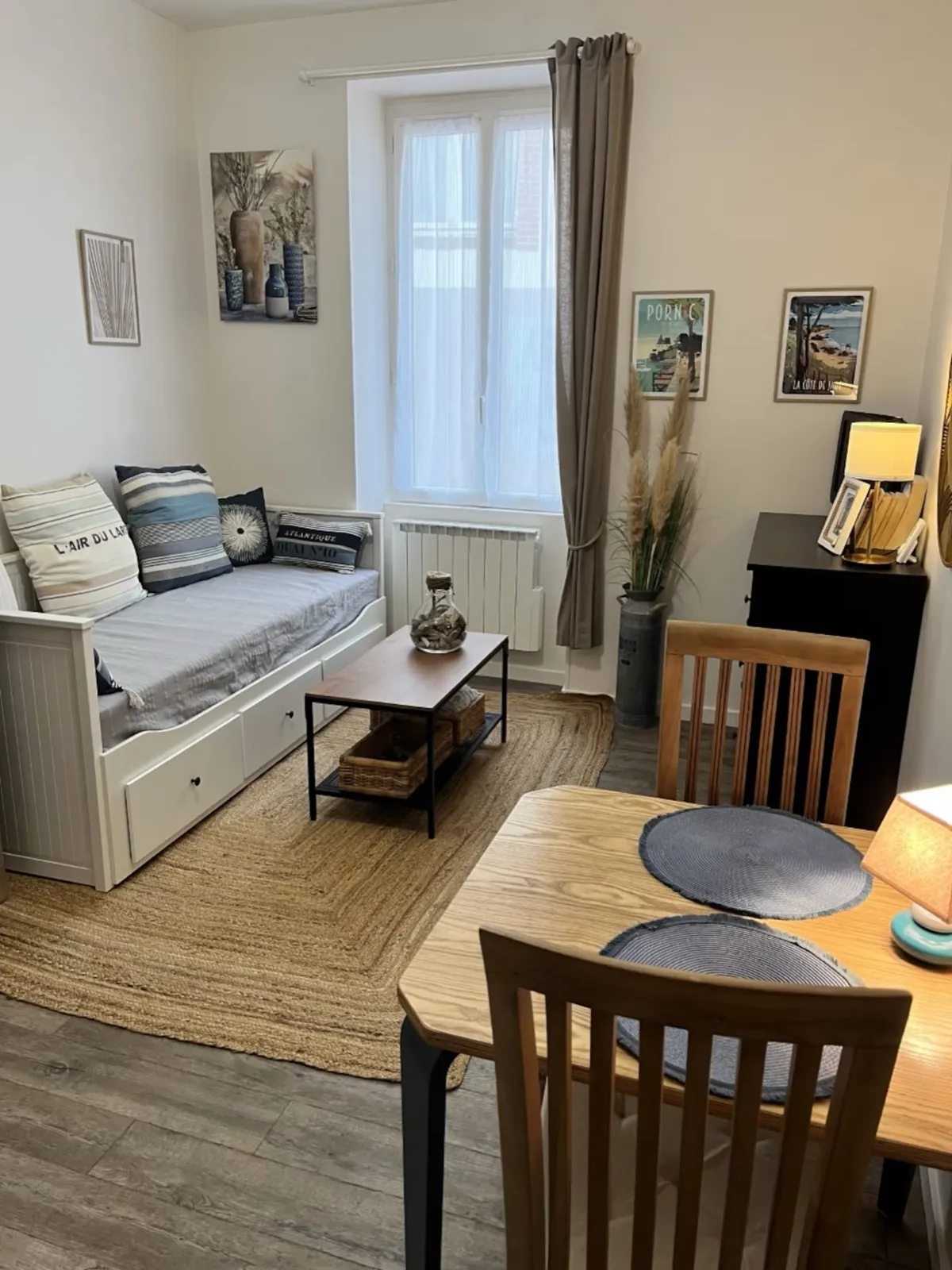 Vue d’ensemble du studio : canapé-lit, fenêtre, coin repas et affiches de Pornic