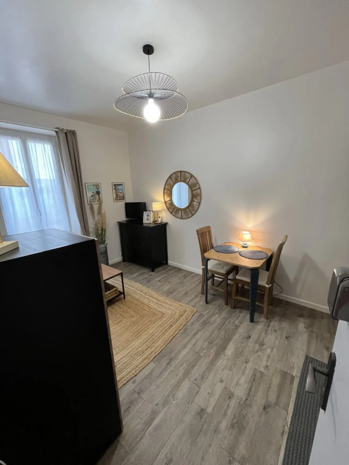 Coin repas avec table en bois pour deux, miroir en rotin et suspension design